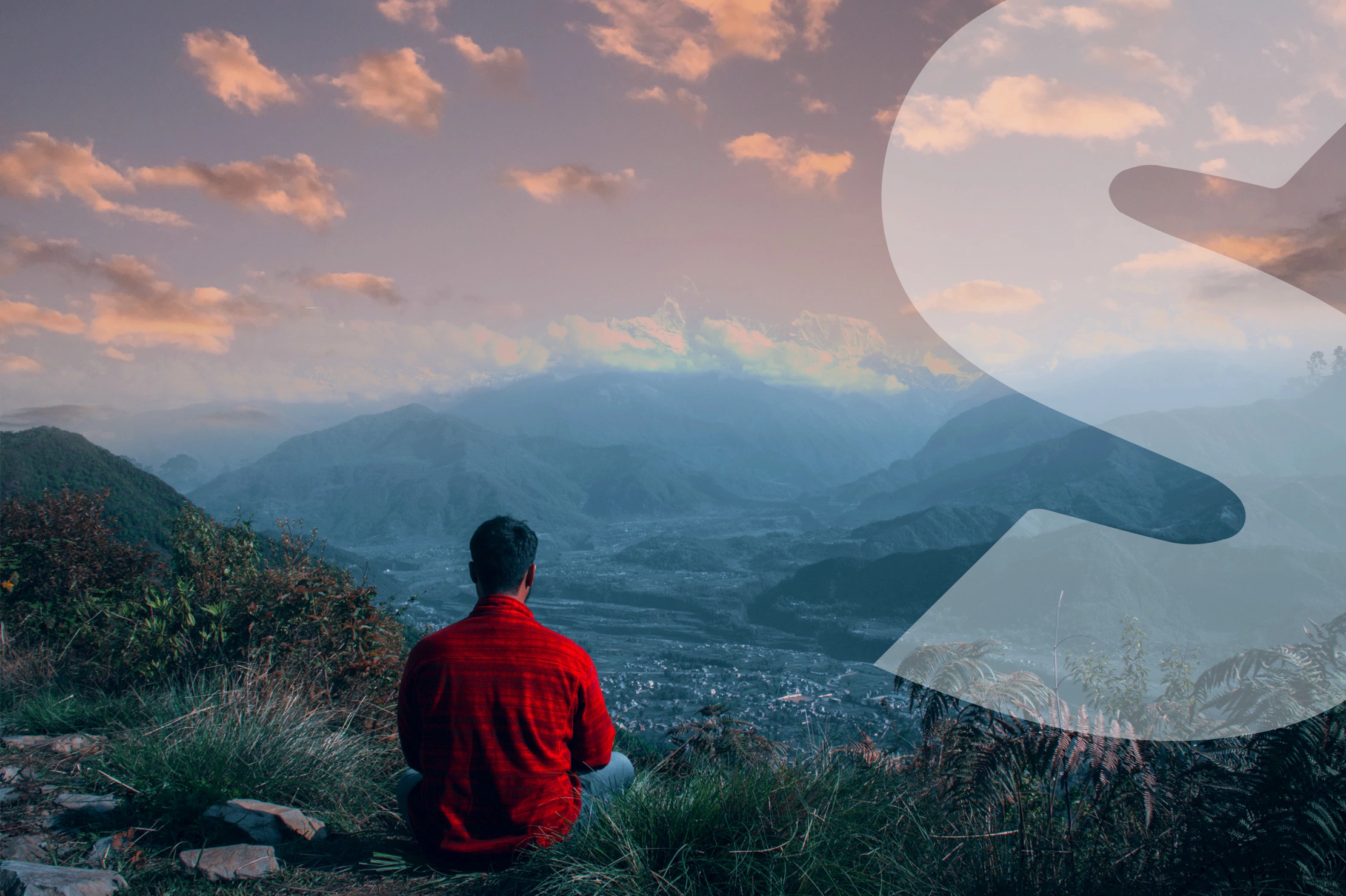 man sitting on hill over looking mountains